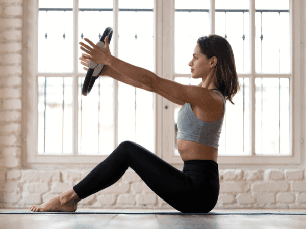 Mulher praticando Pilates para aliviar dores nas costas com postura correta.